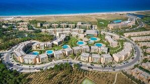 A resort with multiple buildings, swimming pools, and a beach view.