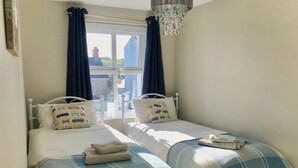 Un dormitorio con dos camas, cada una con almohadas a juego y una colcha azul y blanca a cuadros.