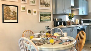 Un comedor con una mesa redonda, sillas y una cocina al fondo.