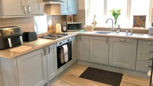 Una cocina moderna con armarios grises, horno empotrado, microondas y estufa a gas.