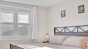 A bedroom with a bed, a nightstand, a lamp, and a window with curtains. - Beautiful 2-bedroom house with AC and fast WiFi in Belleville (Belleville)