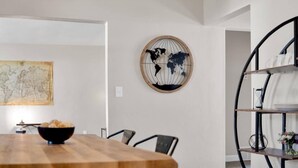 A dining area with a wooden table, chairs, a globe wall art, and a black metal shelf with plates. - Beautiful 2-bedroom house with AC and fast WiFi in Belleville (Belleville)