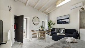 A modern living room with a dining area, a sofa, and a TV. - Alca Arias Suite 20 (Faro)