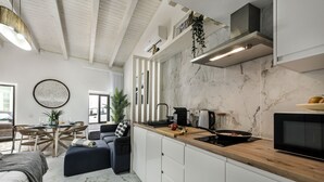 A modern kitchen with white cabinets, a wooden countertop, and a built-in microwave. - Alca Arias Suite 20 (Faro)