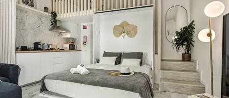 A modern bedroom with a bed, bedside tables, a desk, and a staircase.