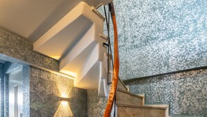 A modern staircase with a wooden handrail, marble steps, and a textured wall with a light fixture. - The Han Residence Halic Hotel (Istanbul)