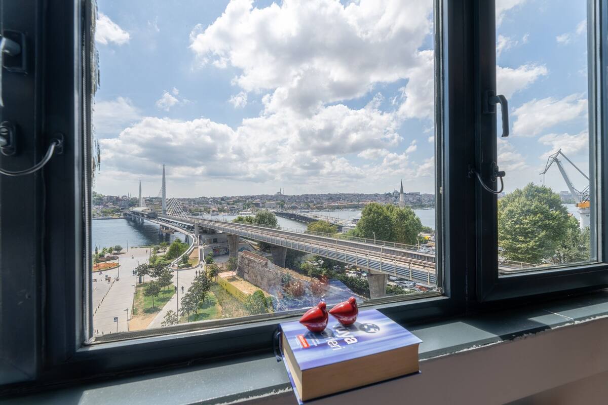 A view from a window overlooking a bridge, a river, and a cityscape.