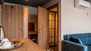 A modern hotel room with a wooden dining table, a blue sofa, and an air conditioning unit on the wall. - The Han Residence Halic Hotel (Istanbul)