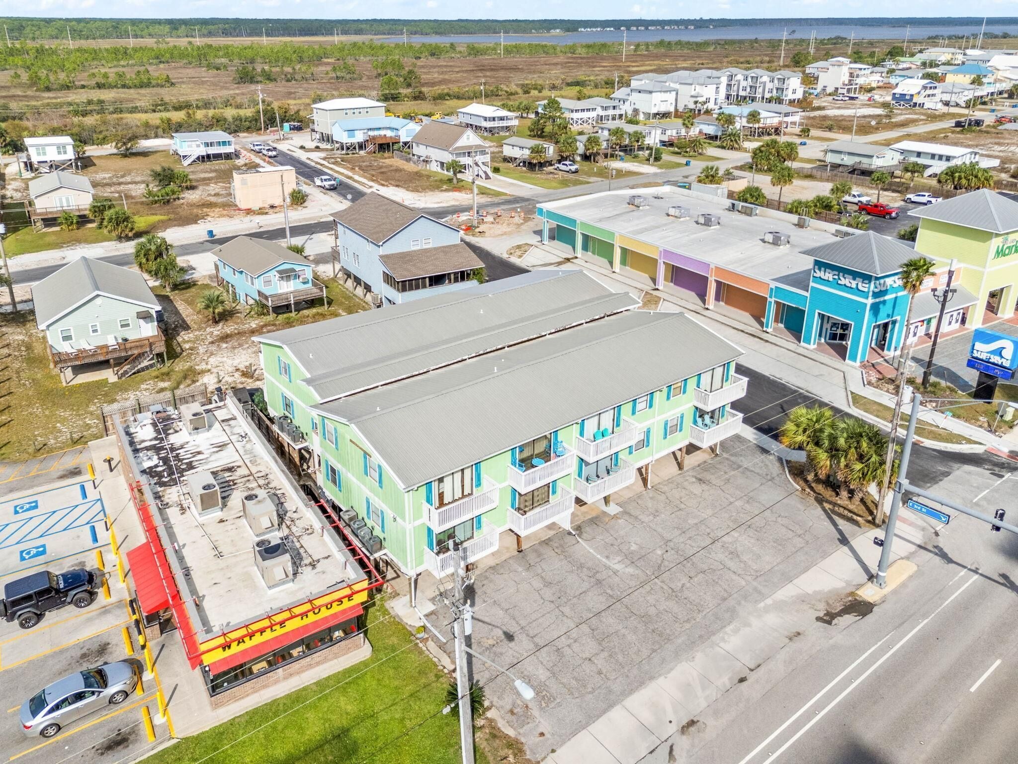 A multi-story building with a flat roof, a parking lot, and a nearby restaurant.