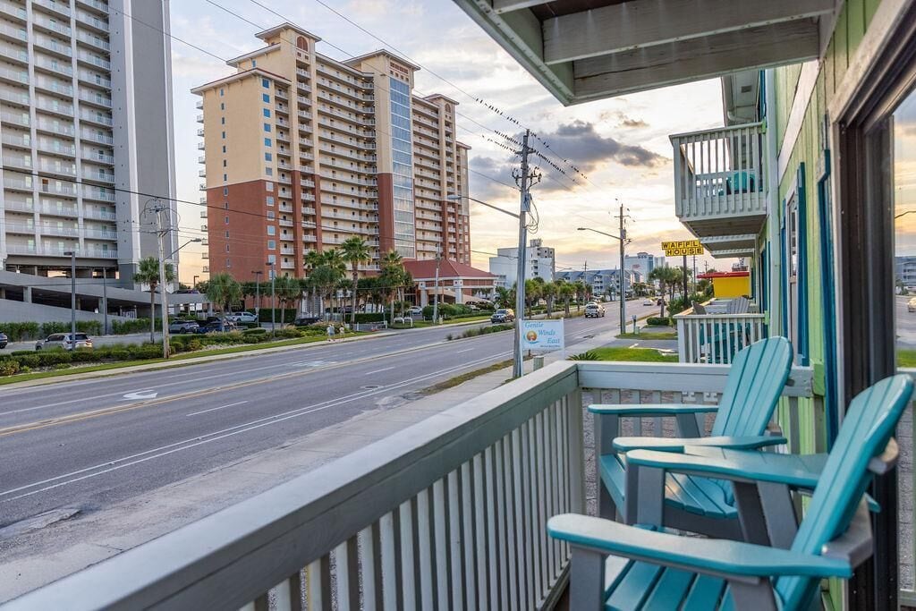 A hotel balcony with chairs, a view of a multi-story building, and a sign for 'Watemite House'.