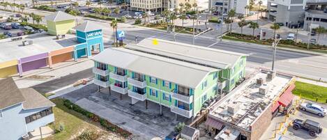A multi-story hotel with a flat roof, located near a beach and parking area.