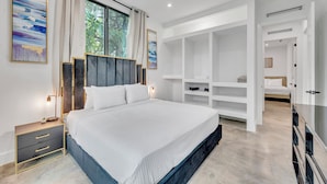 Ein modernes Schlafzimmer mit einem großen Bett, integrierten Regalen und Blick auf Grün.