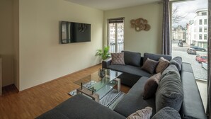 Ein modernes Wohnzimmer mit einer großen Couch, einem Glastisch und einem wandmontierten Flachbildfernseher.