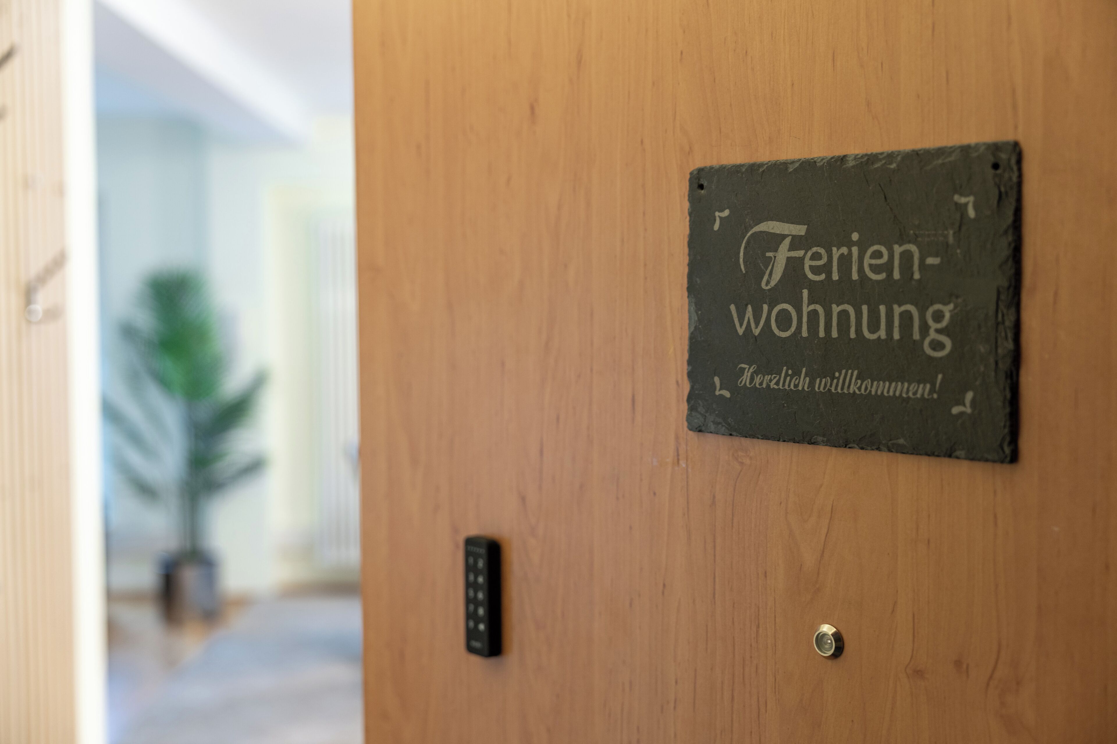 Une porte avec une pancarte indiquant « Ferienwohnung » et « Herzlich willkommen ! » (Bienvenue !).