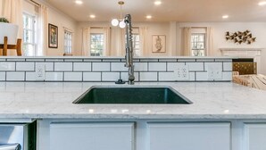 Eine geräumige Küche mit einer großen Kochinsel, weißen Schränken und einem modernen Wasserhahn.