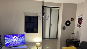 Un salon moderne avec un téléviseur à écran plat, une table basse, un fauteuil poire et un canapé.