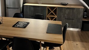 Une cuisine moderne dotée d’un îlot central intégré, d’appareils électroménagers en acier inoxydable et d’une table à manger en bois avec des chaises noires.
