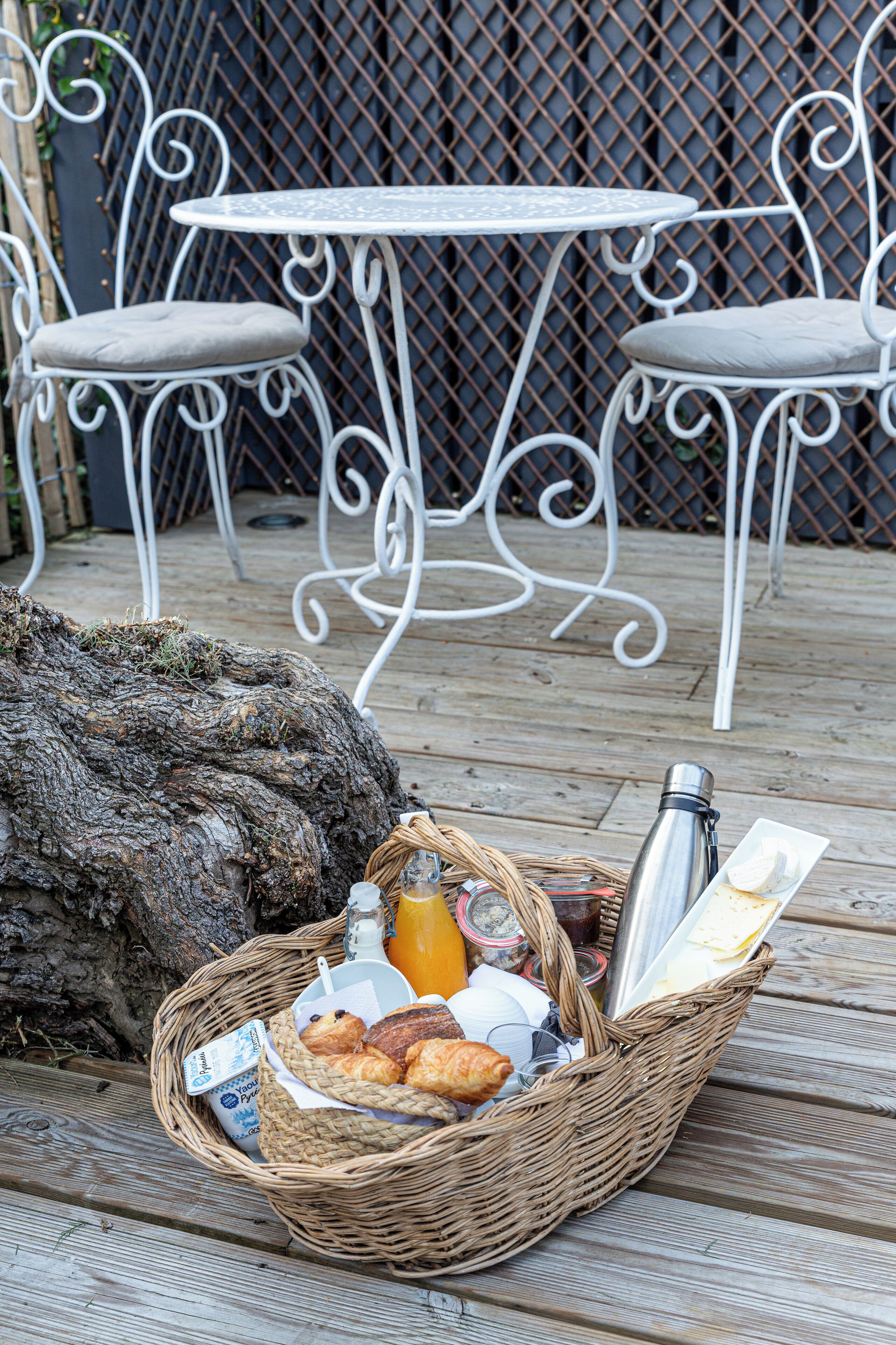 A wicker basket with food items and a bottle on a wooden deck.