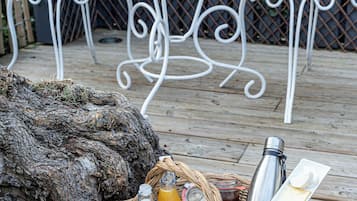 A wicker basket with food items and a bottle on a wooden deck.