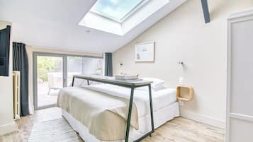 A bedroom with a skylight, a bed, a bedside table, and a view of the outside.