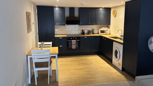 A compact kitchen with dark cabinets, a wooden countertop, a built-in oven, a microwave, and a washing machine.