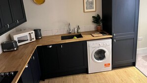 A compact kitchen with a microwave, toaster, sink, and washing machine.