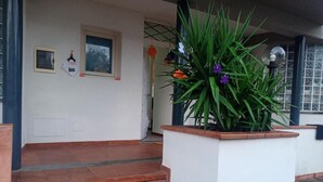 A staircase leading to a white door with a 'BOO' sign, a potted plant with green foliage, and a window with a view of trees.