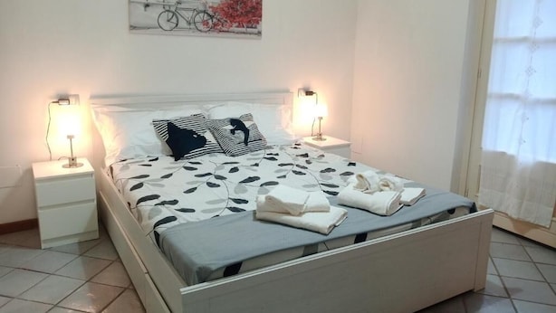A neatly made bed with a patterned bedspread, two bedside lamps, and a wall-mounted artwork.