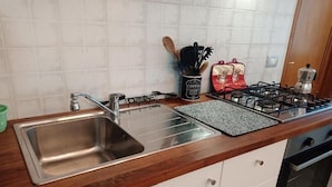 A kitchen with a stainless steel sink, a gas stove, and a coffee maker.