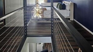 A high-ceilinged room with a sloped ceiling, a staircase, and a bed with pillows. - Scotty's sunny spot (Doniphan)