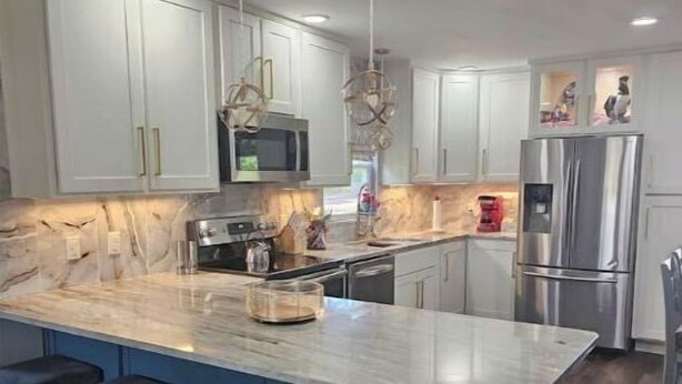 A modern kitchen with white cabinets, a marble island, and stainless steel appliances. - Scotty's sunny spot (Doniphan)