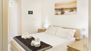 Ein modernes Schlafzimmer mit einem großen Bett, einem Nachttisch, einer Wandlampe und einem Beistelltisch.