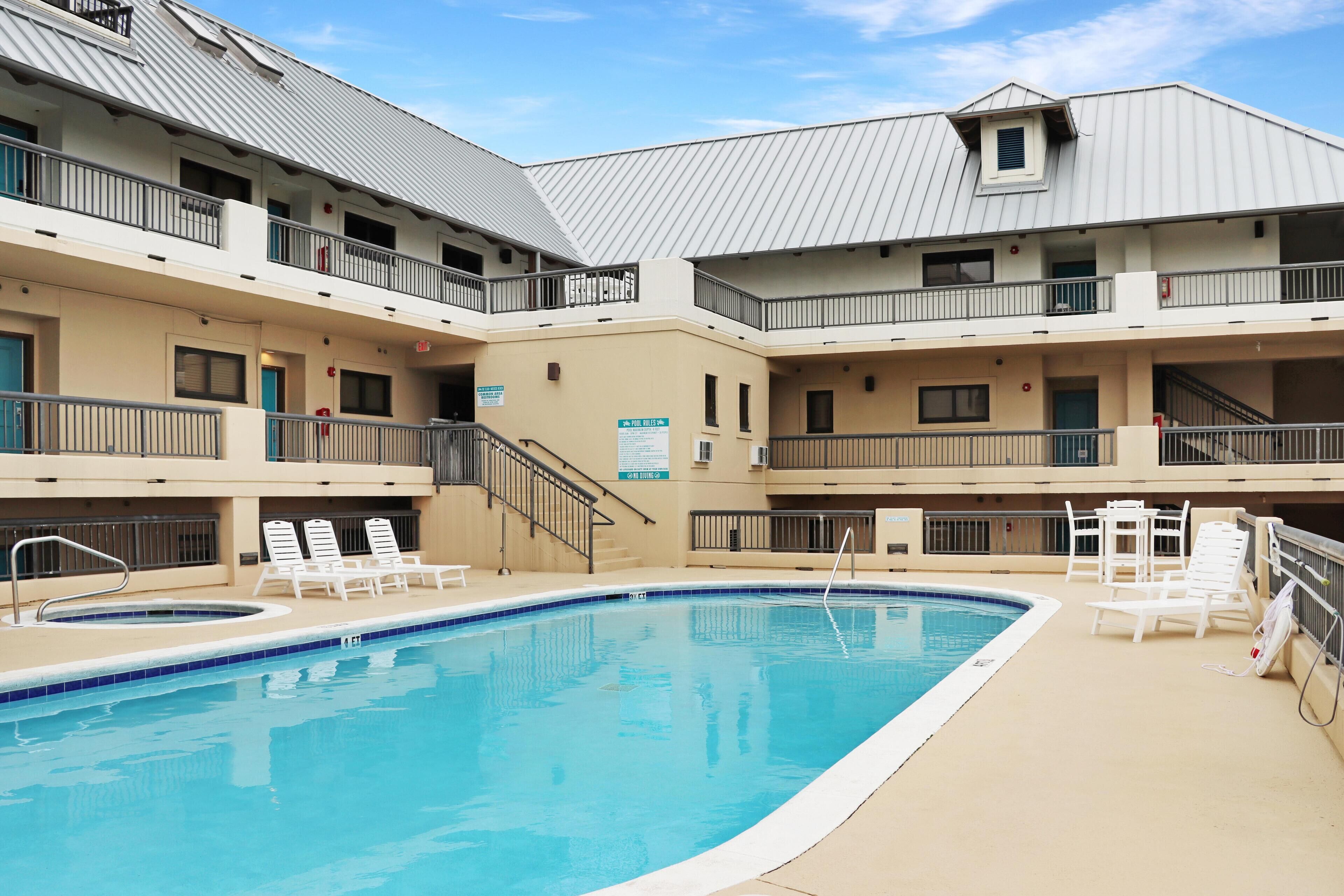 Un hôtel doté d’une piscine, de plusieurs balcons et d’un espace extérieur couvert aménagé avec des chaises longues.