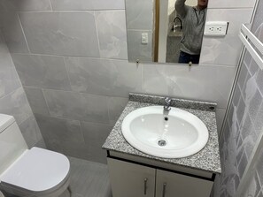 Bathroom features a toilet, sink with granite countertop, and mirror.