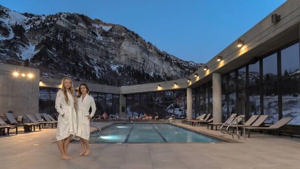 A pool area with lounge chairs and a mountain backdrop.