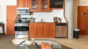 A compact kitchen with wooden cabinets, a microwave, an oven, and a coffee maker.