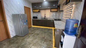 A modern kitchen with a refrigerator, stove, and water dispenser. - Tobas Apartment (Uyo)