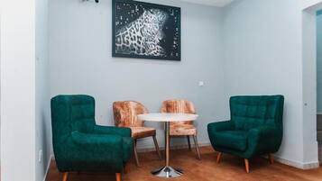 A room with two green armchairs, a small round table, and a leopard print chair.
