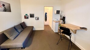 A compact living space with a sofa, a small kitchenette, and a desk. - 5 min to Parc des Princes • Studio 18 m²<br>Boulogne (Boulogne-Billancourt)