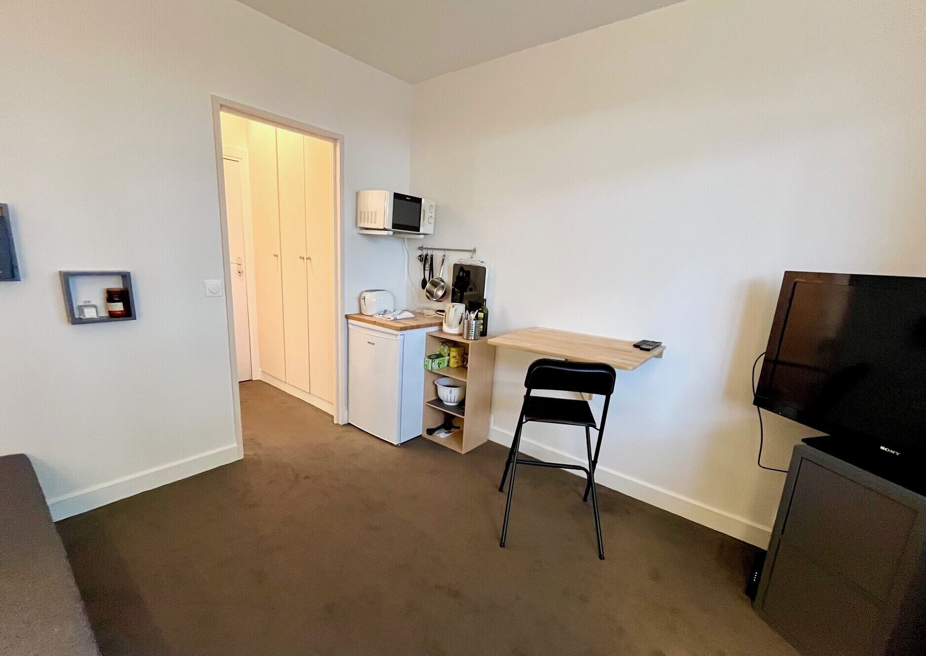 A compact living space with a kitchenette, a dining area, and a TV.