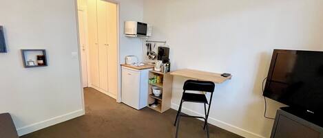 A compact living space with a kitchenette, a dining area, and a TV.