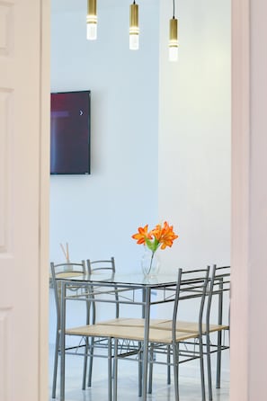 A dining area with a table and chairs, a vase with flowers, and pendant lights. - 15 Minutes From Manhattan Private Two Bedroom Apartment in Astoria/LIC/Queens NY (Queens)