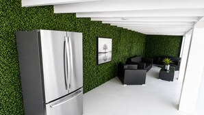 Une cuisine moderne dotée d’un réfrigérateur en acier inoxydable, d’un mur vert et d’un coin repas avec des meubles noirs.