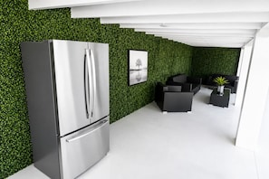A modern kitchen with a stainless steel refrigerator, a green wall, and a dining area with black furniture. - Miami Relax Getaway/4BR/BBQ/Heated Pool & Fun (Miami)