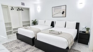Une chambre moderne avec deux lits, un dressing et une table de chevet avec une lampe.