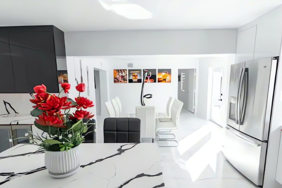 A modern kitchen with white cabinetry, a marble countertop, and a stainless steel refrigerator.
