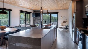 A modern kitchen with a central island, built-in appliances, and a stone accent wall.