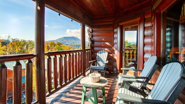 Eine Holzdar Terrasse mit Blick auf Berge, einem Tisch und zwei Adirondack-Stühlen.