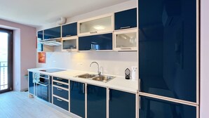 A modern kitchen with a double sink, stainless steel appliances, and a large window.
