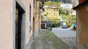 A narrow cobblestone street flanked by buildings with arched doorways and windows.